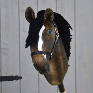 Hobby Horse Sundance avec licol noir de Hobby Horse LarDen, robe brune, liste blanche, crinière noire en fil et licol noir, rappelant un étalon pur-sang fougueux, présenté sur un fond en planches de bois gris clair.