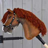Hobby Horse Cooper avec licol noir de Hobby Horse LarDen, avec tête brune en tissu, crinière en fil, liste blanche sur le nez et monté sur un bâton en bois. Conçu pour ressembler à un élégant cheval de sport, il est idéal pour des aventures de dressage imaginatives et est photographié ici devant un fond en bois gris.
