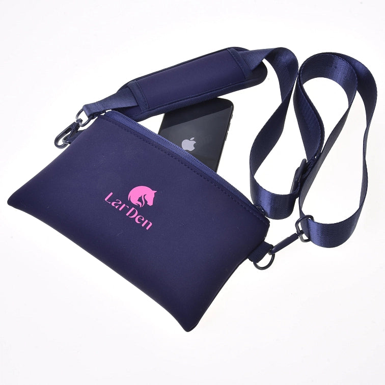 A navy blue LarDen crossbody bag with a pink logo, shown with an adjustable strap and a black smartphone partially inside the zippered pouch—perfect for carrying essentials to your next Hobby Horsing event—on a white background.