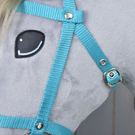 Close-up of a plush horse toy with light gray fabric, black and white stitched eye, and the Hobby Horse LarDen Black bridle with reins from strap turquoise.