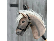 Hobby Horse Happy Boy avec licol noir de Hobby Horse LarDen, un Hobby Horse cheval hanovrien gris et blanc avec licol noir et crinière blanche, présenté sur fond en bois avec charnières et loquet en métal.
