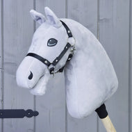 Construis ton cheval, Hobby Horse gris clair avec crinière noir-gris-blanc marquante et bride noire fixée à un bâton en bois, présenté sur fond de mur en bois gris.