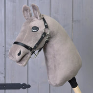 Construis ton cheval de related_to_12441055625556, Hobby Horse en peluche taupe avec bride noire et crinière en fil blanc sur bâton en bois, présenté devant un fond en panneaux de bois gris.