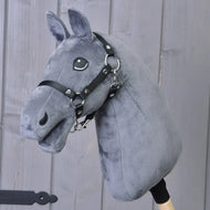 A dark grey “Build your horse” hobby horse by related_to_12441055625556, featuring a black bridle and mounted on a wooden stick, is displayed in front of a wooden wall.