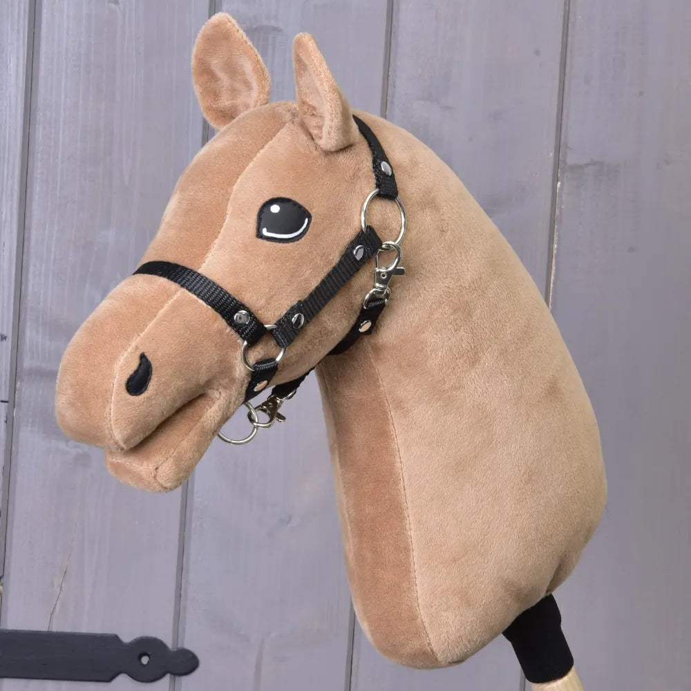 Construis ton cheval en peluche, avec fourrure marron clair couleur caramel, bride noire et yeux cousus, posé contre un fond en bois avec des crinières chocolat soigneusement confectionnées qui ajoutent un charme supplémentaire.