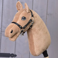 Construis ton cheval de related_to_12441055625556, jouet en peluche avec fourrure brun clair couleur caramel, crinière cappuccino, bride noire et œil brodé amical, posé devant un mur en bois gris.