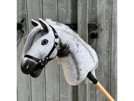 Hobby Horse Naivy avec licol noir de Hobby Horse LarDen, présenté devant une porte en bois rustique, montrant son style Appaloosa gris et blanc et sa crinière détaillée.