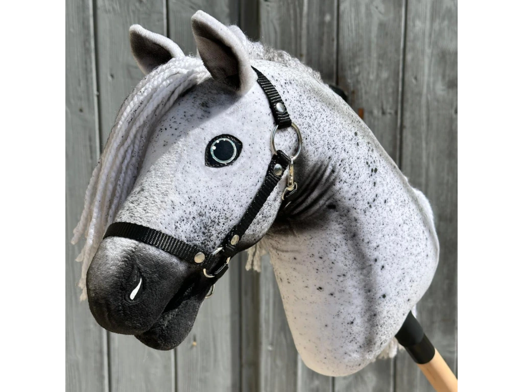 Gros plan sur Hobby Horse Naivy avec licol noir - taille S de Hobby Horse LarDen, étalon gris réaliste avec crinière blanche et licol noir, monté sur un bâton sur fond rustique en bois.