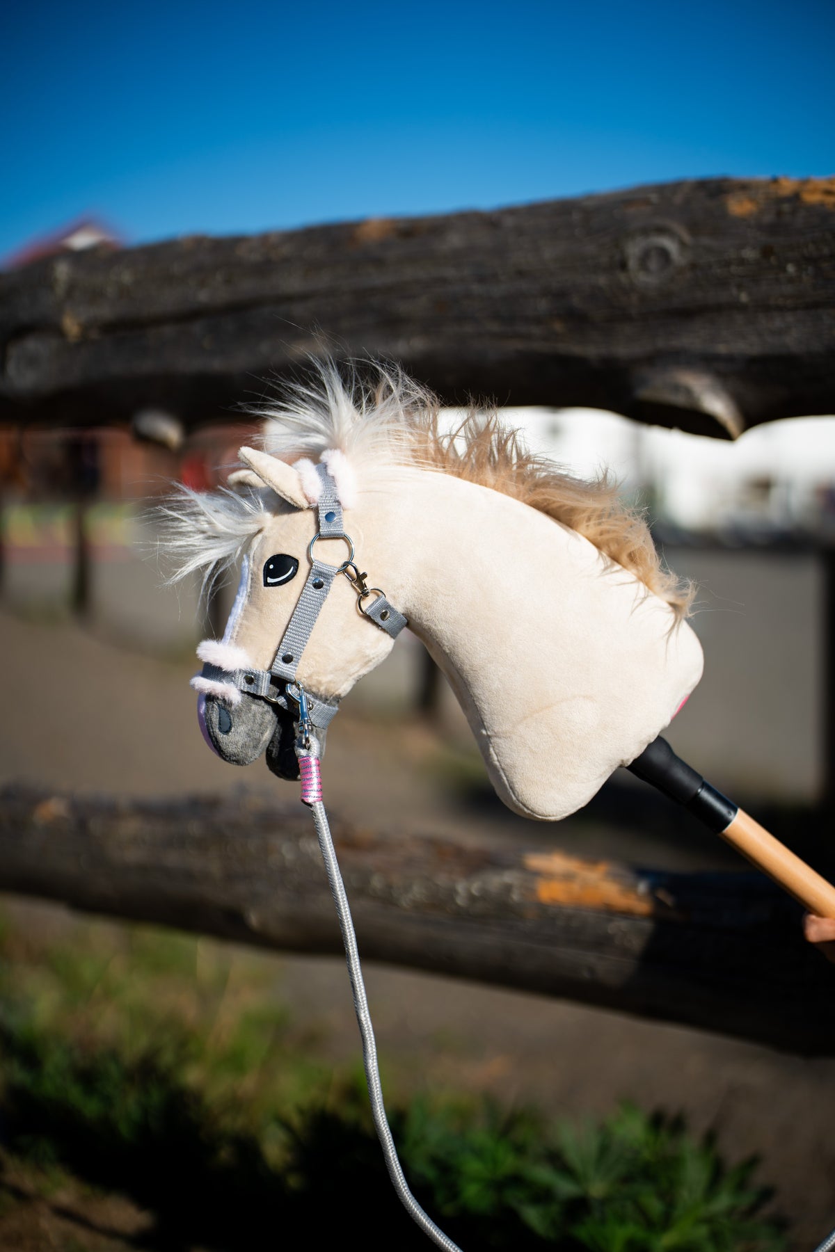 Hobby Horse Pixie devant une clôture en rondins avec un licol gris avec fourrure et une longe grise à enroulement rose