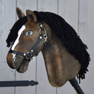 Hobby Horse Sundance avec licol noir de Hobby Horse LarDen, avec tête brune inspirée de la rapidité des étalons, crinière en fil noir, liste blanche et licol noir, le tout monté sur un solide bâton en bois devant un mur en bois gris.