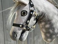 Gros plan sur Hobby Horse Untamed Sweety de Hobby Horse LarDen montrant la tête de jument grise avec un licol noir et un œil en verre réaliste, sur fond en bois.